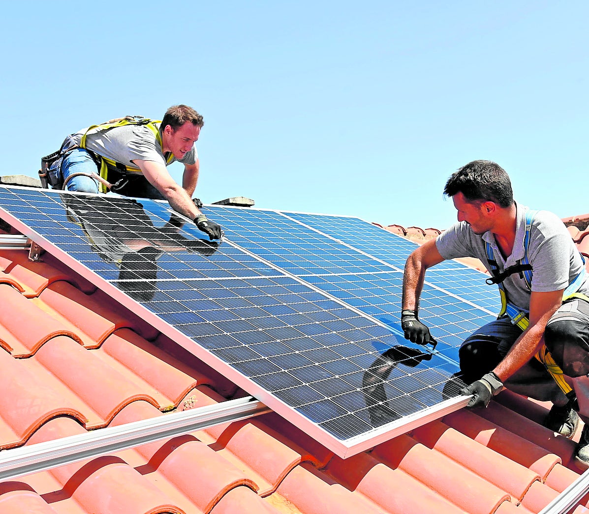 Unos operarios instalan paneles solares en el tejado de una vivienda.