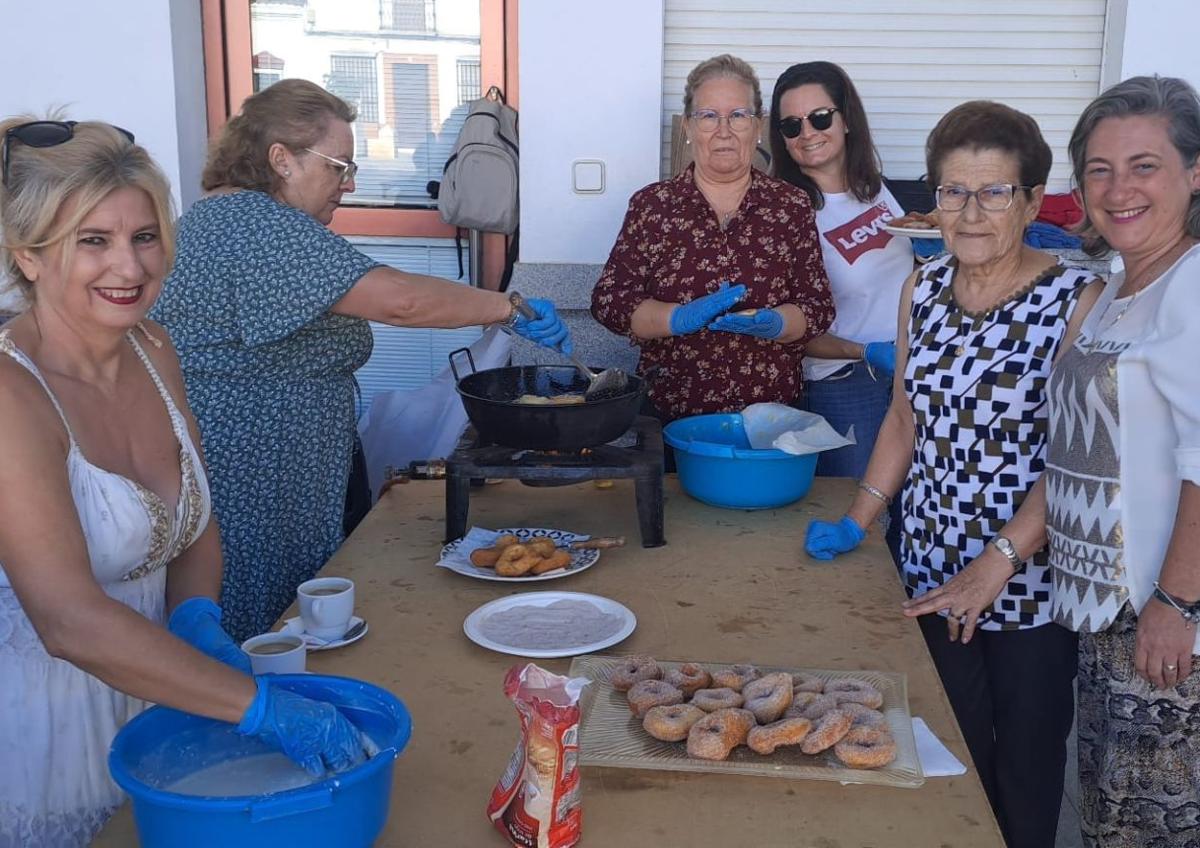 Imagen secundaria 1 - Arriba, componentes de la Banda de Cornetas y Tambores 'Villa de Alconchel' tras la diana floreada que han dado este sábado. Abajo, a la izquierda, grupo de mujeres de la Asociación 'La Esperanza' y de la Hermandad del Cristo, durante la elaboración de dulces. A la derecha, ejemplares del libro de fiestas del Cristo 2024.