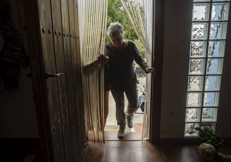 Elena Martínez, paciente con ELA, subiendo las escaleras de su casa con ayuda de su mujer.