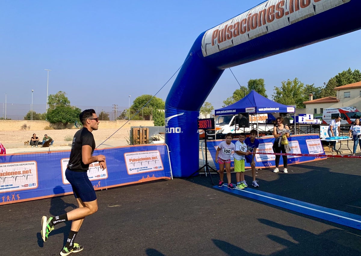 Imagen secundaria 1 - Tres momentos de la carrera solidaria, con la salida en la imagen superior, el ganador, Julián polo, en el momento de entrar en la meta, y un grupo de participantes, sobre estas líneas.