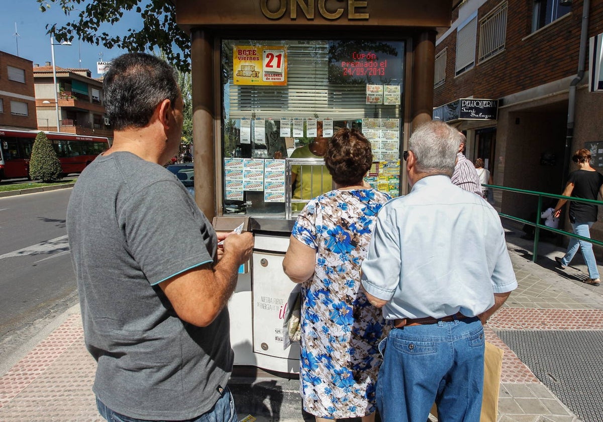 Varias personas esperan en una cola para comprar un décimo de lotería de la ONCE.