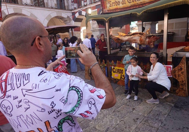 Mercedes Campos con sus hijos se hacen una foto delante del plato estrella de la fiesta, el cerdo asado.