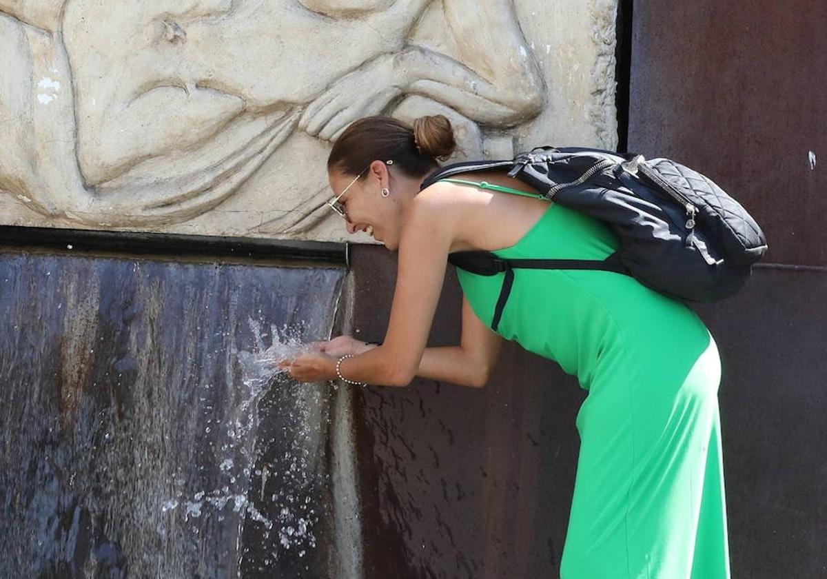 Una mujer se refresca en una fuente de Mérida.