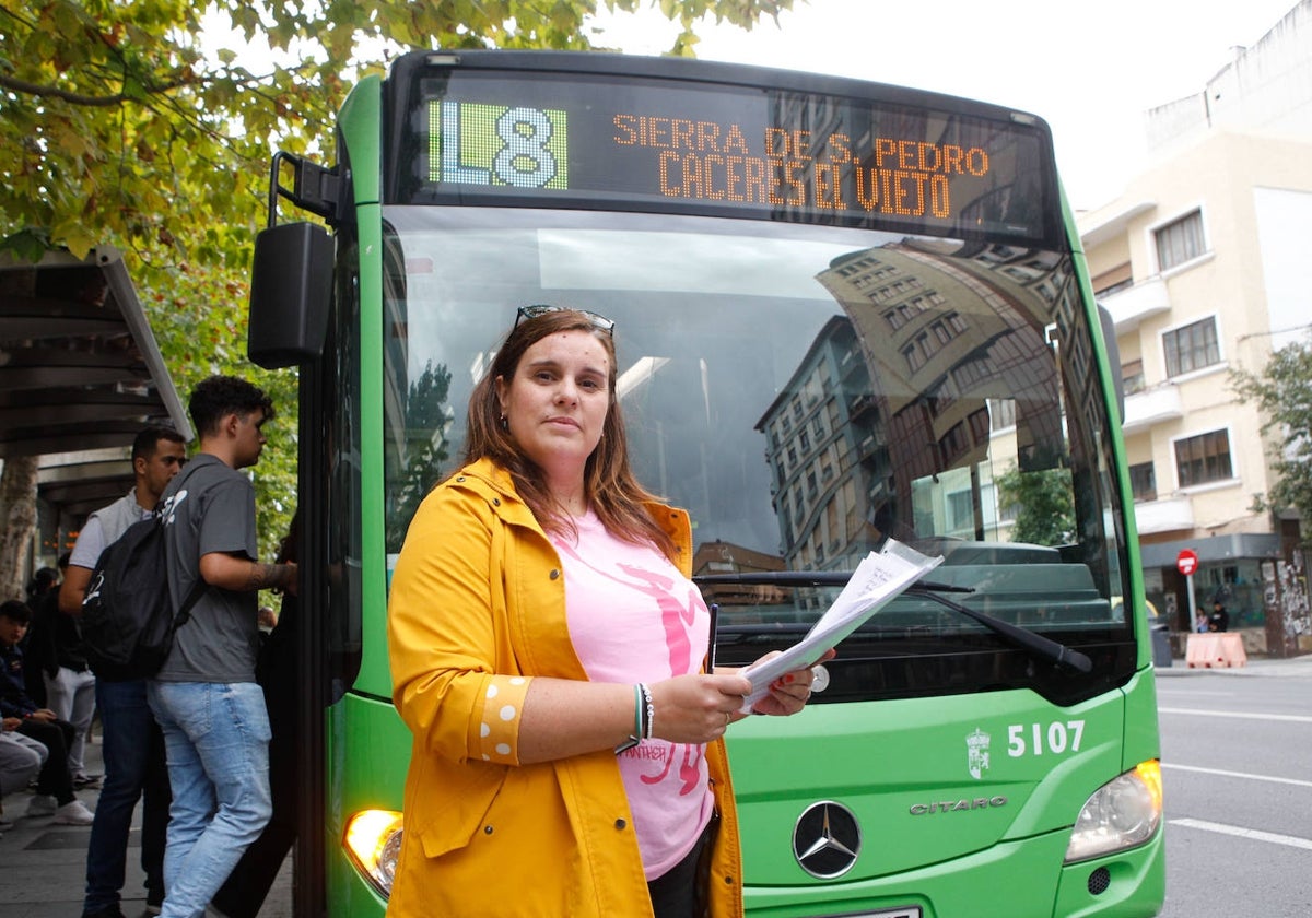 Victoria Campos, con una de las hojas de recogida de firmas, delante de un bus de la línea 8.