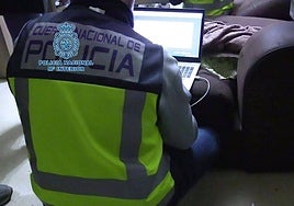 Un agente de la Policía Nacional examina un ordenador incautado en una operación contra ciberdelincuentes