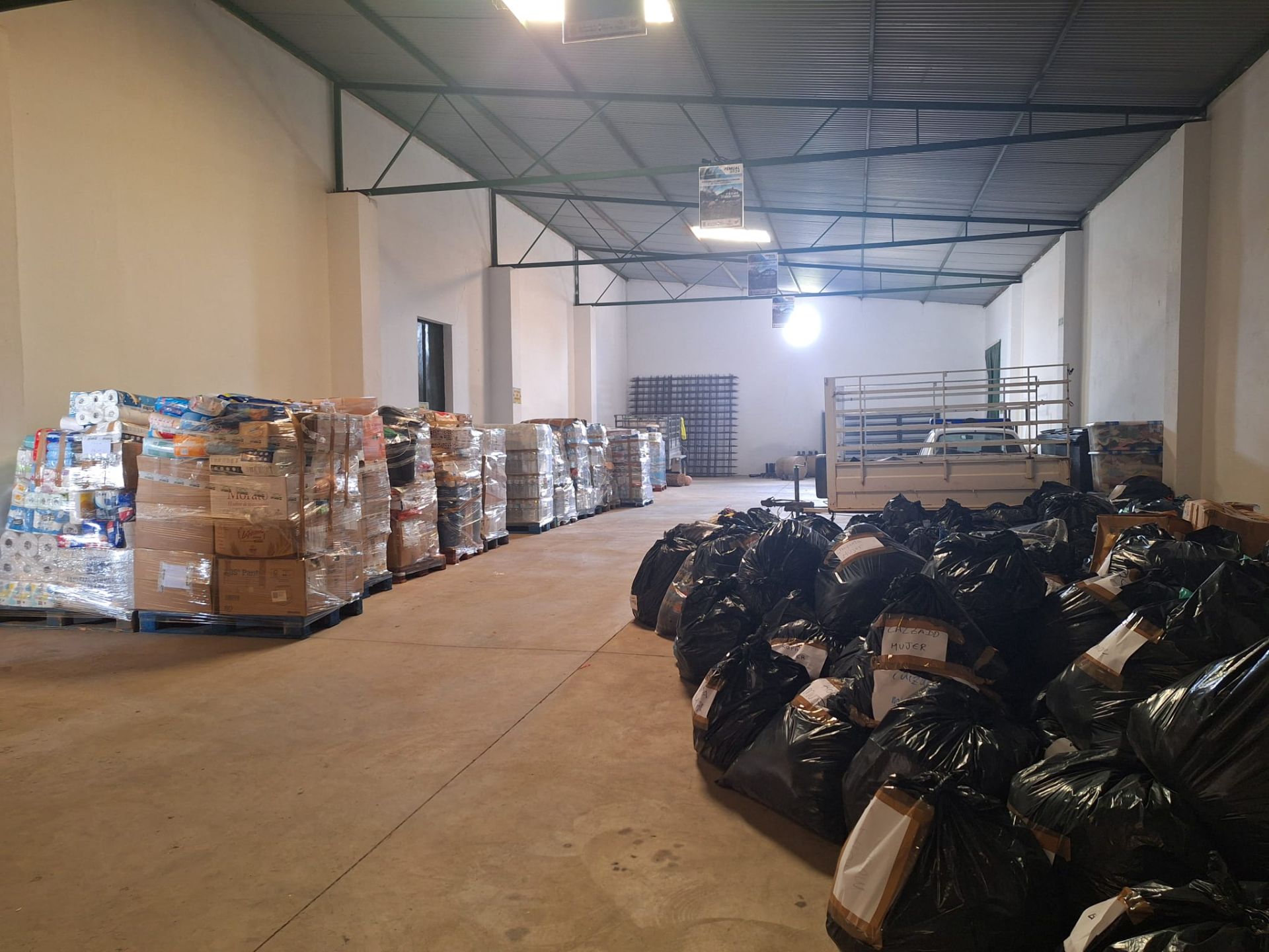 Una treintena de palets con productos de primera necesidad y decenas de bolsas con ropa seleccionada ya están listas para cargar en el tráiler.