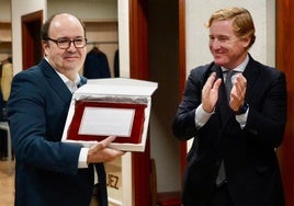 Felipe Velázquez, responsable de la sastrería familiar, recoge la placa conmemorativa de las manos del alcalde de Badajoz.