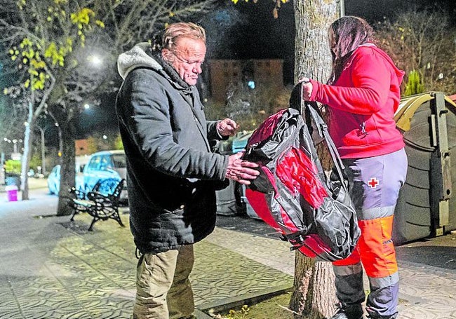 Una voluntaria entrega a una persona sin hogar una mochila.