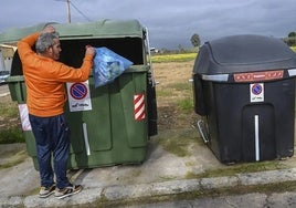 Un pacense llevando la basura al contenedor de residuos sólidos urbanos.