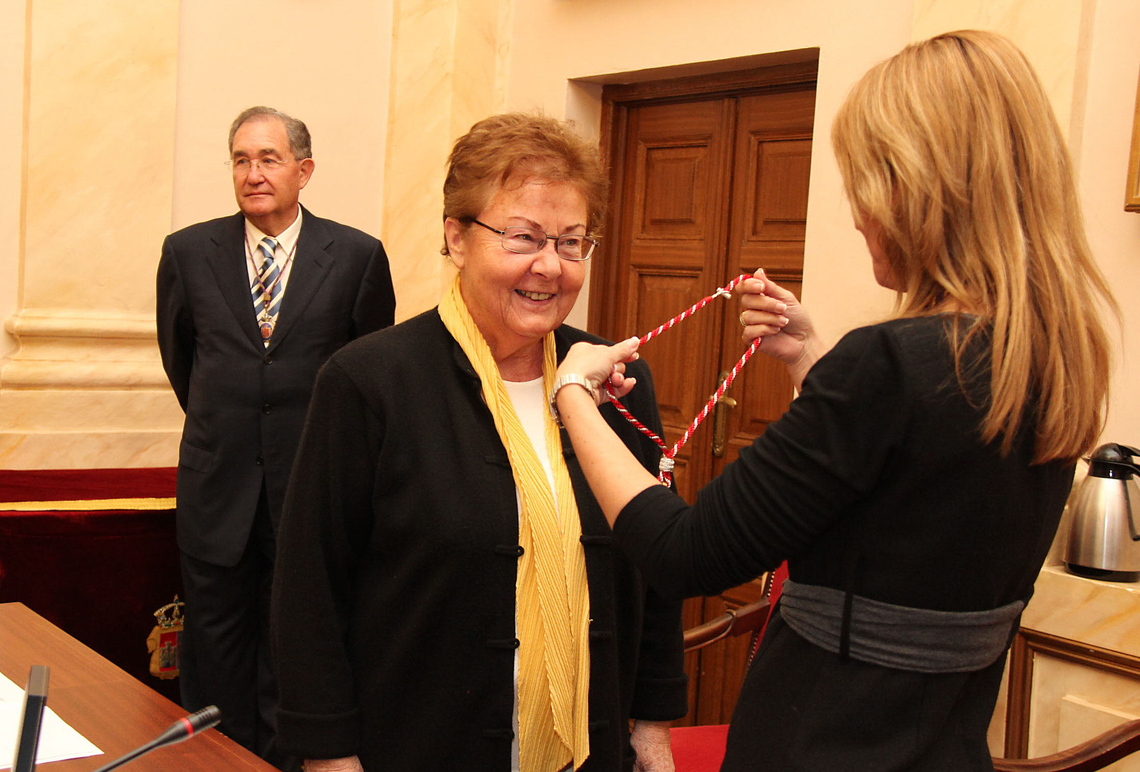 La exalcaldesa Elena Nevado impone la medalla de la ciudad a la galerista alemana Helga de Alvear en el salón de plenos del Ayuntamiento de Cáceres.