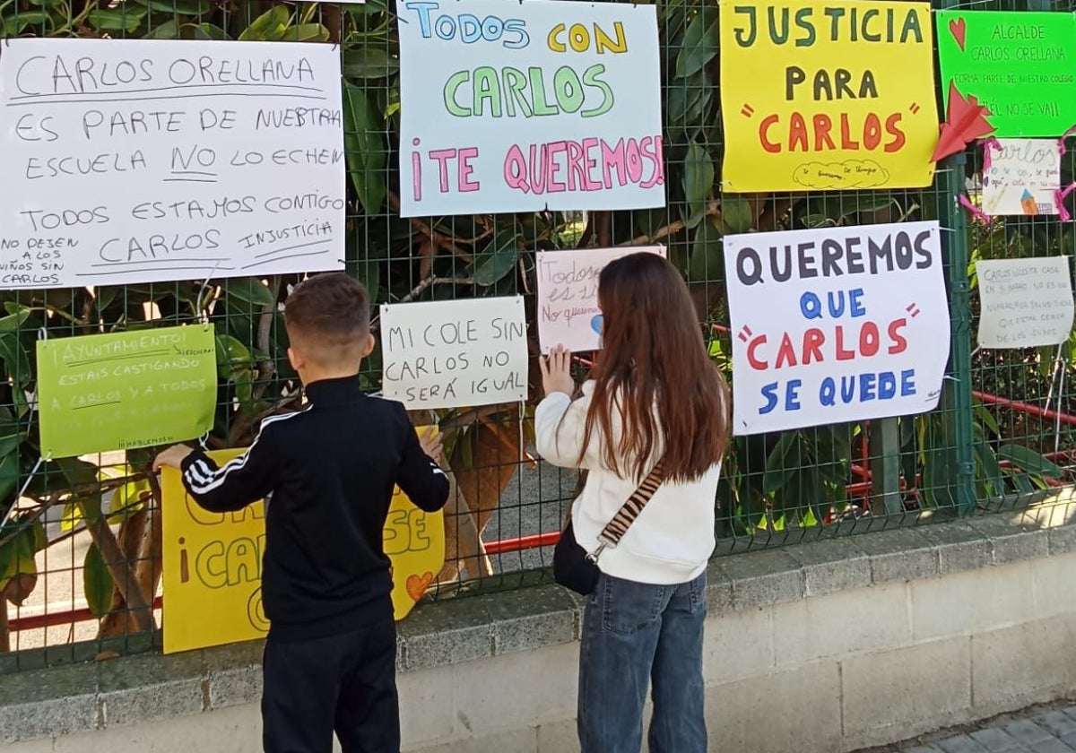 Dos alumnos del colegio Juan Vázquez colocan carteles en la verja del colegio Juan Vázquez.