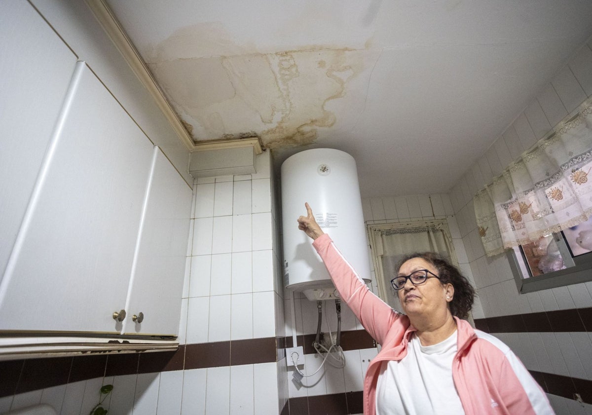 Imagen principal - Agustina López señala las manchas de humedad en el techo. En otra imagen, las escaleras del bloque siguen sin mantenimiento. Debajo, vivienda tapiada tras haber sido okupada.