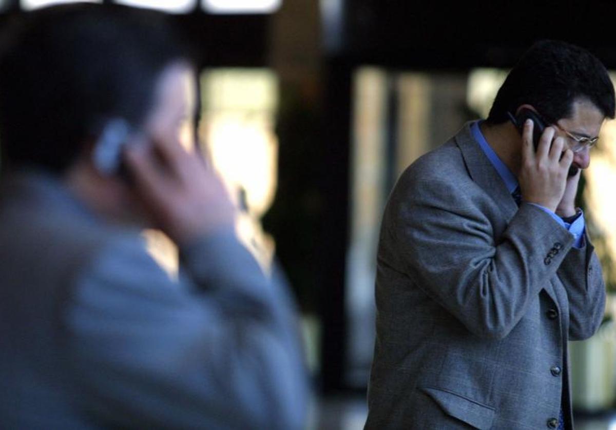 Personas hablando por teléfono en la calle.