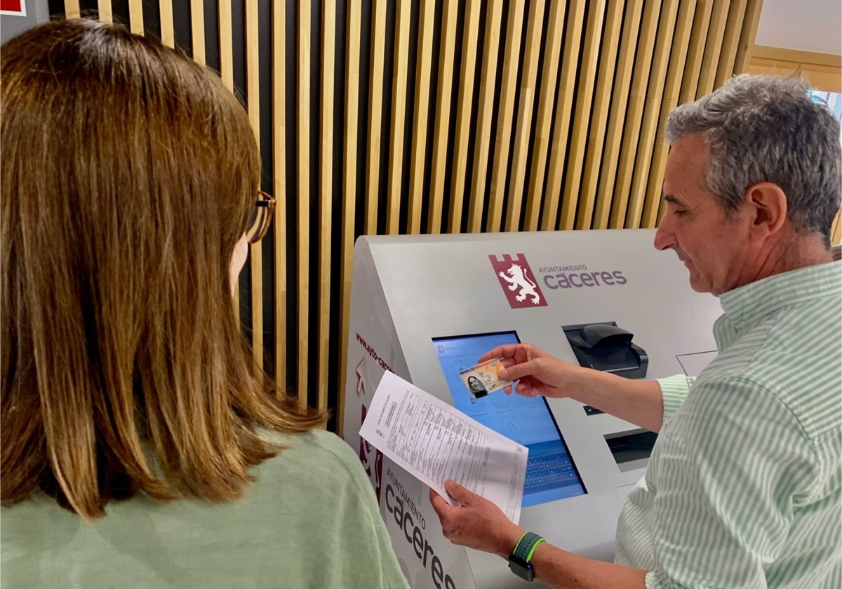 Un funcionario ayuda a una mujer en sus gestiones en un dispositivo de atención telemática del Ayuntamiento.