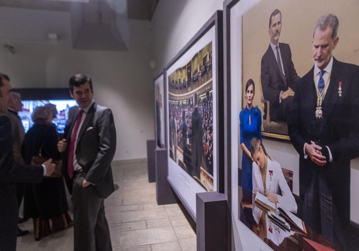 Asistentes a la inauguración observan una de las fotografías de la muestra.