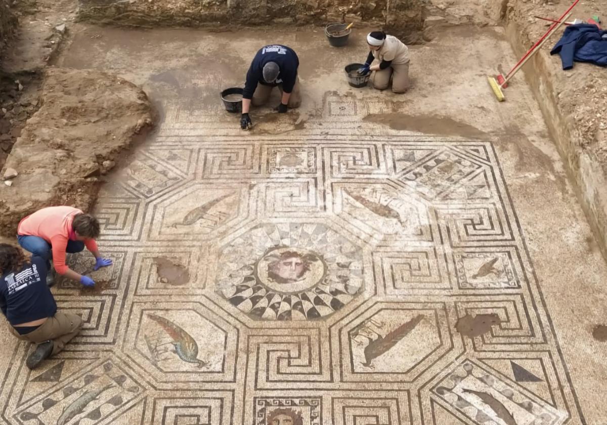 Alumnos trabajadores de Barraeca limpiando el pavimento de mosaico que se protegerá.