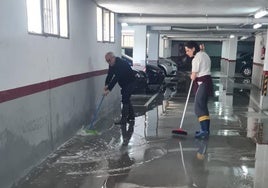 Los vecinos achicando agua en el garaje.