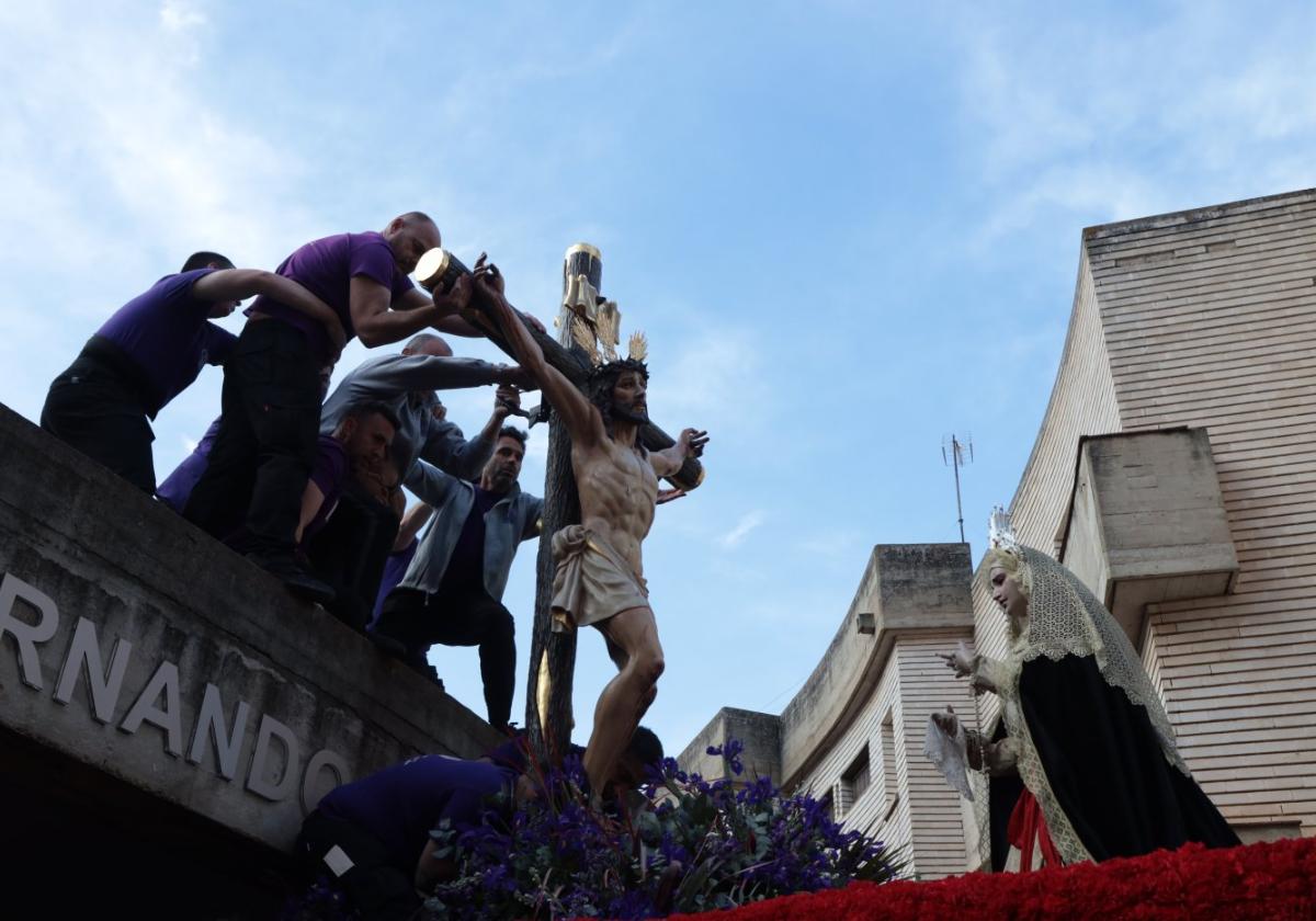 Los costaleros terminan de 'montar' el paso del Misterio del Calvario a la puerta de la parroquia de San Fernando; a la derecha, María Santísima de la Misericordia.