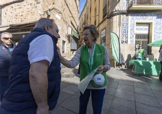 Una voluntaria de la AECC de Cáceres coloca una pegatina a un donante.
