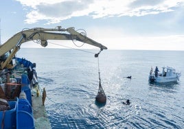 Un barco saca del agua el depósito donde se envejece debajo del agua el vino Habla del Mar.