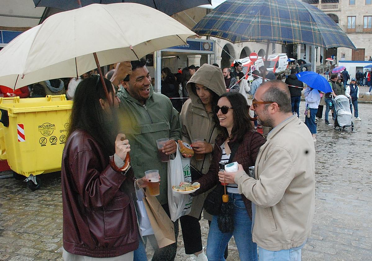 Un grupo de amigos se resguarda de la lluvia bajo el paraguas sin parar de comer queso.