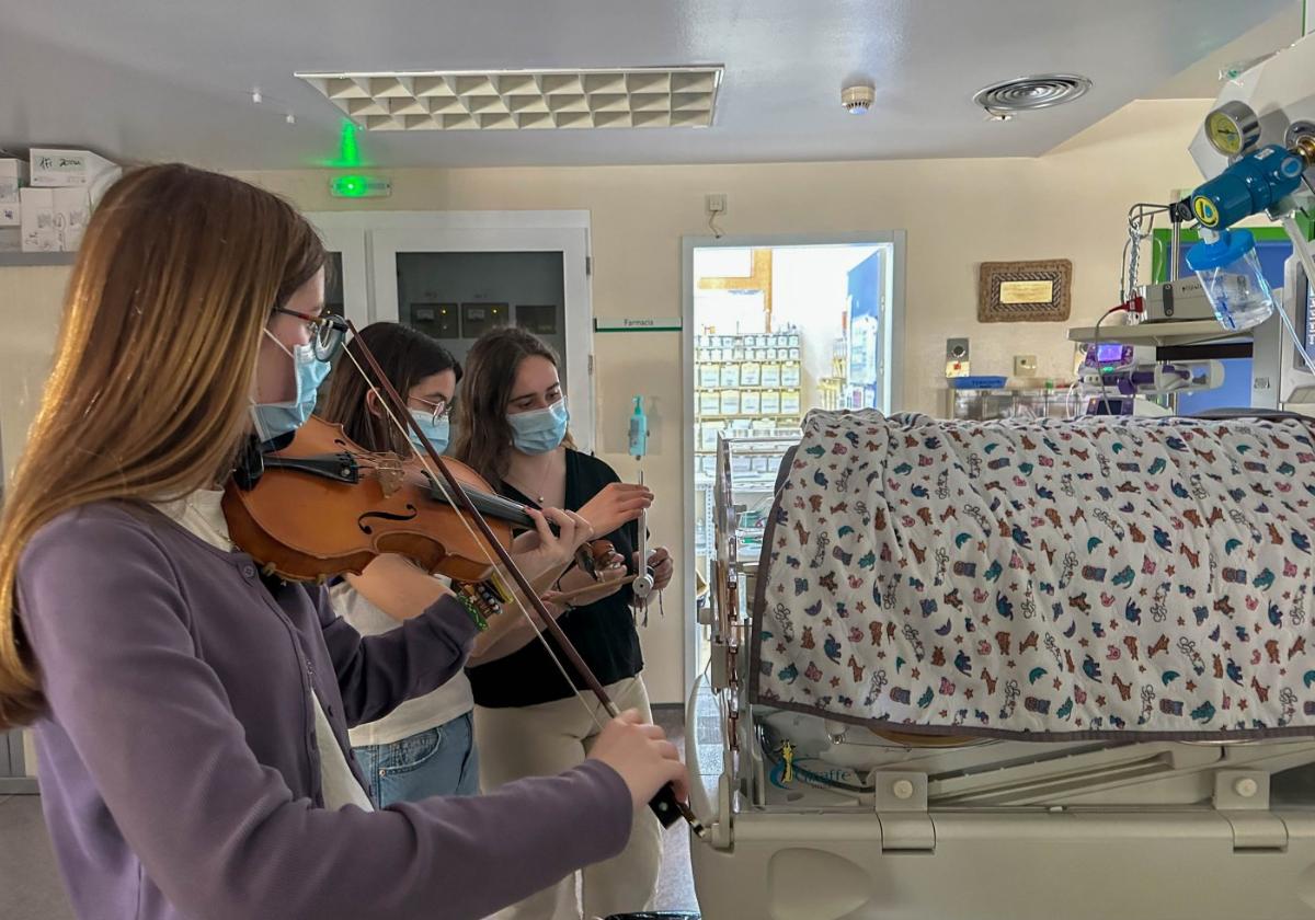 Tres alumnas tocando una misma secuencia rítmica junto a la cuna de los neonatos.