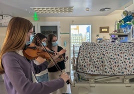 Tres alumnas tocando una misma secuencia rítmica junto a la cuna de los neonatos.
