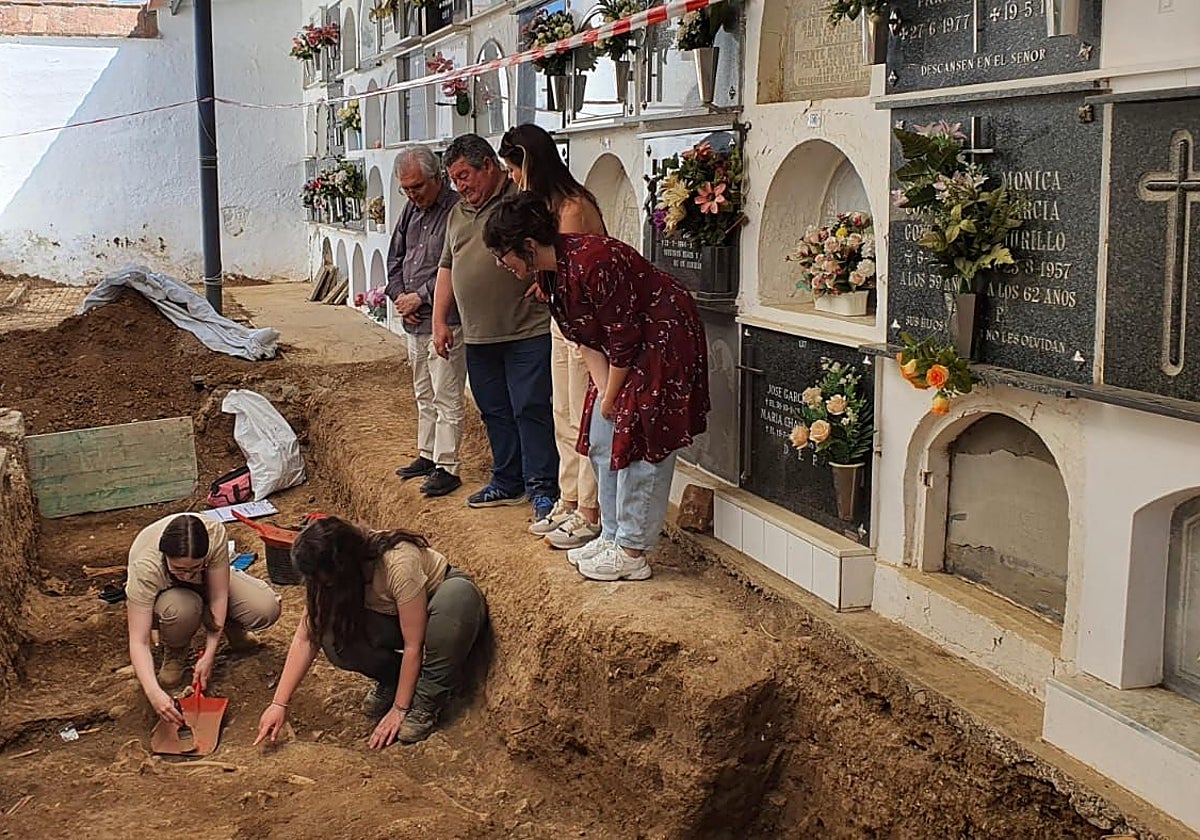 El alcalde de Valverde de Llerena, segundo por la izquierda y personal de la empresa Almena, esta mañana, en el cementerio de la localidad junto a una de las fosas localizadas.