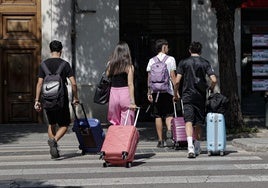 Un grupo de jóvenes cruza la calle con sus maletas.