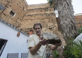 Rodrigo Albarrán, dueño de la casa que linda con la Torre de Caleros, muestra una de las piedras de la construcción que han caído a su patio.