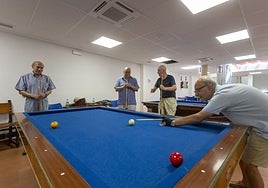 Usuarios del hogar de la Plaza Mayor de Cáceres juegan al billar en la segunda planta del edificio. En el techo, nuevas máquinas de aire acondicionado.