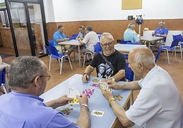 Tres usuarios del centro juegan al tute en la planta baja del hogar de la Plaza.