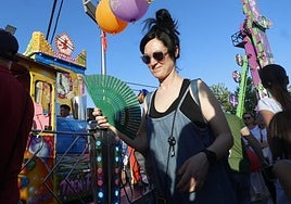 Una mujer se abanica por el calor durante la feria.