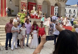 Una familia de Primera Comunión se fotografía ante el altar de las escalinatas municipales.