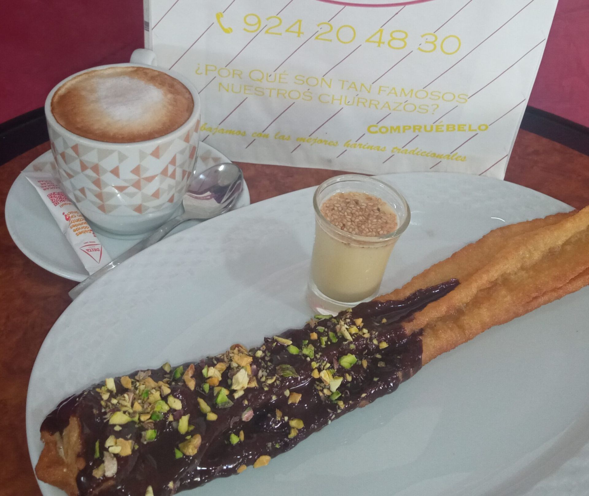 Porra rellena de crema de pistacho con cobertura de chocolate y chupito de chocolate blanco