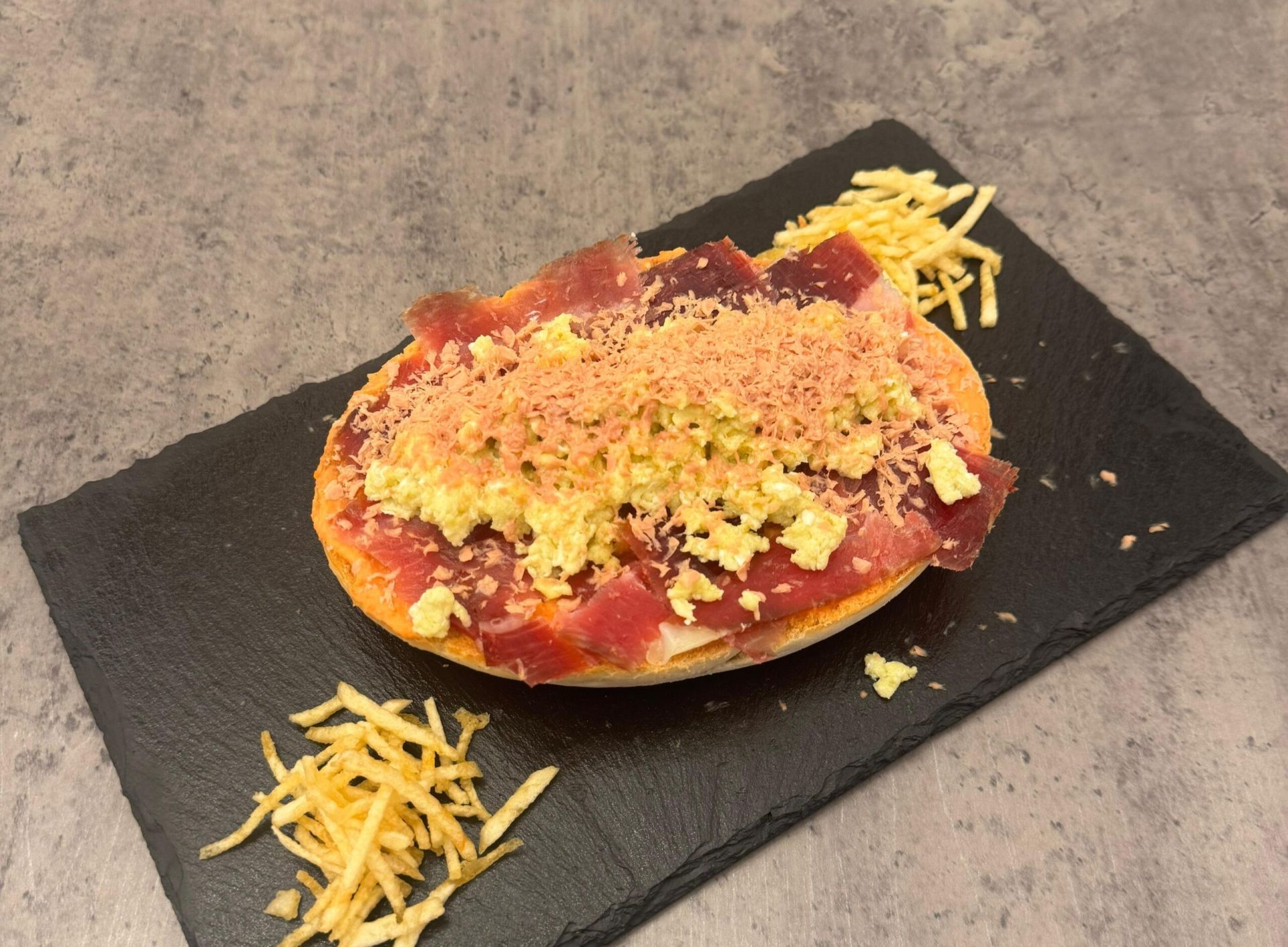 Mollete tostado con base de tomate estilo salmorejo con Aove, jamón ibérico, revuelto de tortilla y virutas de foie. Para los que les guste el contraste dulce/salado tendrán la opción de añadirle una mermelada de higos.