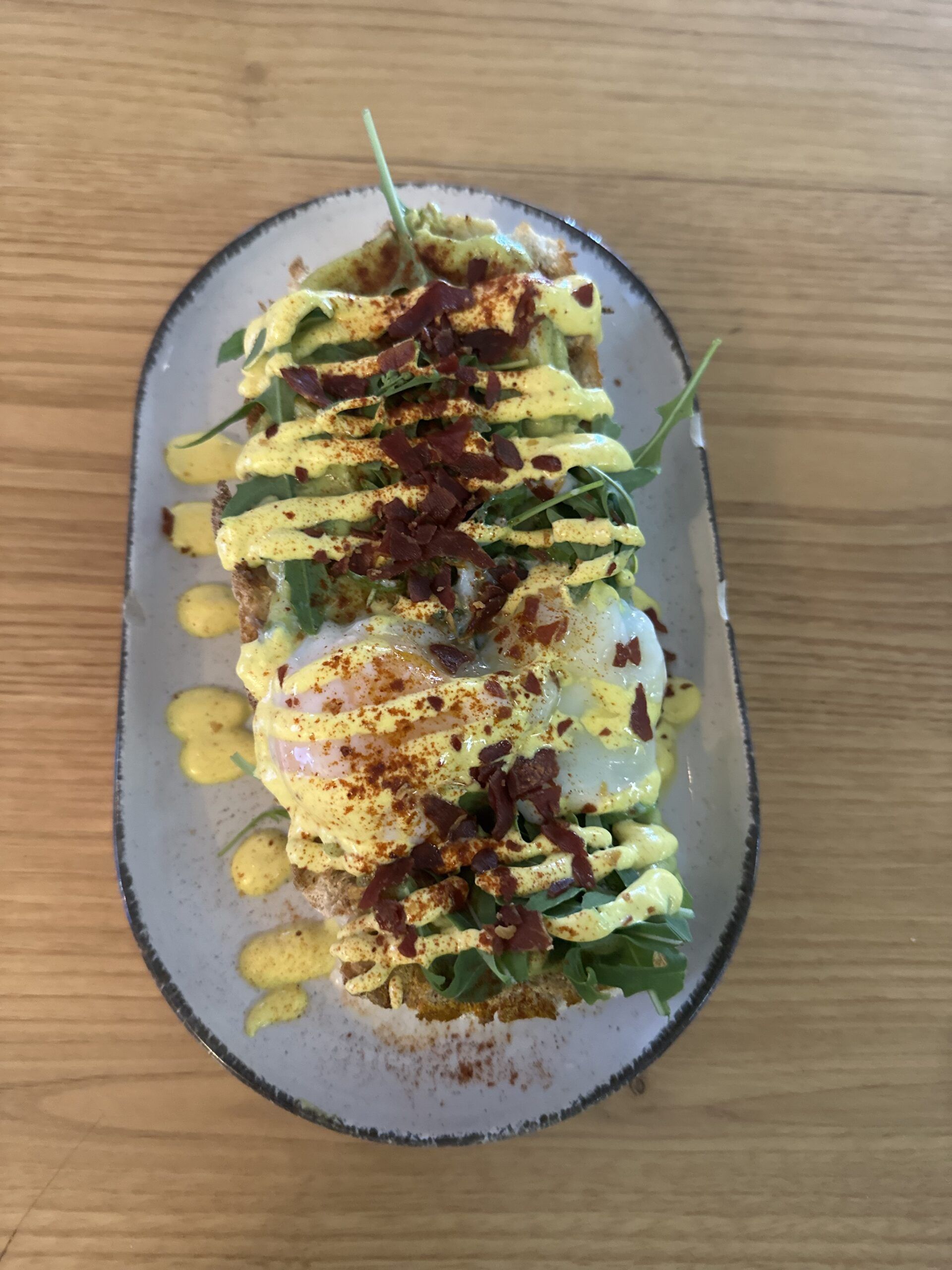 Tostada con crema de aguacate, rúcula, huevo a baja temperatura y nuestra salsa dorada de toques cítricos.