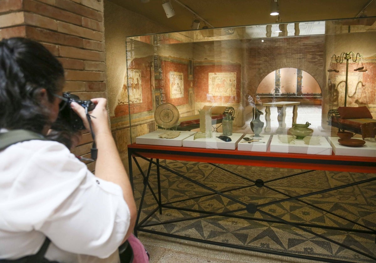 Una mujer realiza fotos a piezas del Museo Romano de Mérida.