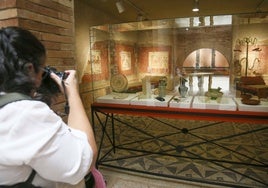 Una mujer realiza fotos a piezas del Museo Romano de Mérida.