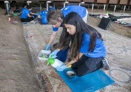 Alumnos del curso de arqueología restauran un mosaico en la Casa del Anfiteatro.