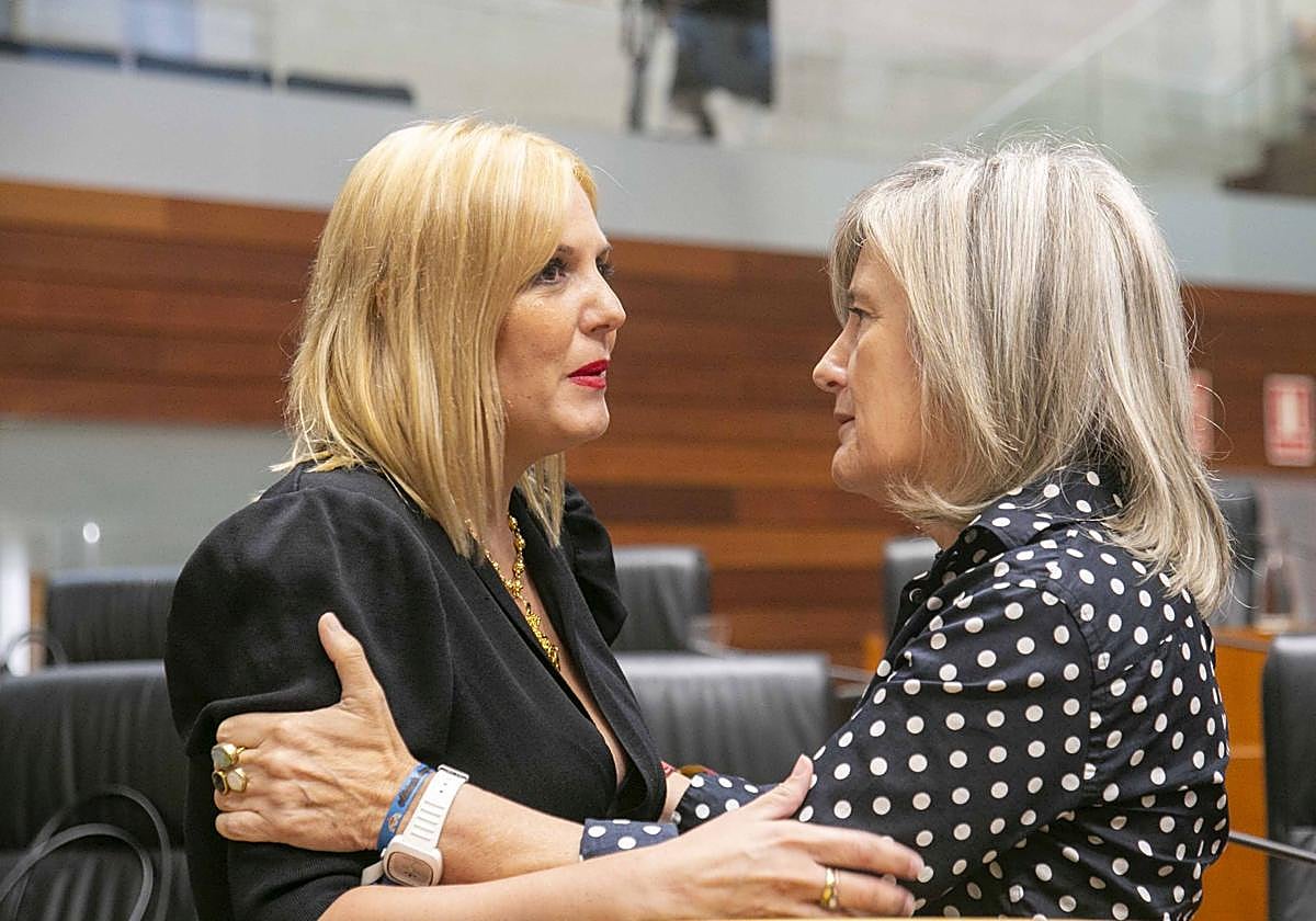Elena Manzano y Victoria Bazaga se saludan antes de un Pleno de la Asamblea de Extremadura.