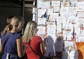 Varias personas buscan pisos de alquiler en tablones en Cáceres, una imagen poco habitual ya ante la falta de anuncios por la escasa oferta.