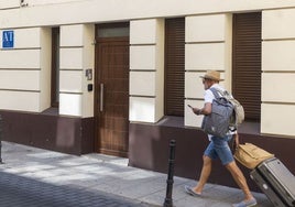 Un viajero pasa delante de un edificio destinado a apartamentos turísticos situado en la calle Parras de Cáceres.