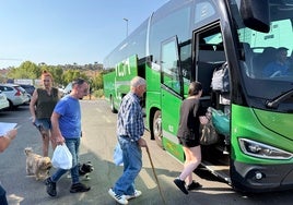 Vecinos desalojados suben en Plasencia al autobús para volver a sus casas.