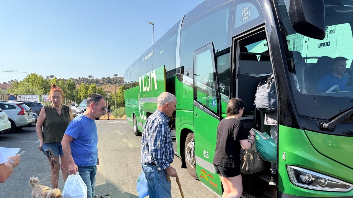 Vecinos desalojados suben en Plasencia al autobús para volver a sus casas.