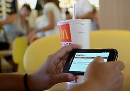Un cliente de Mc Donalds consulta su móvil en un local de Badajoz.