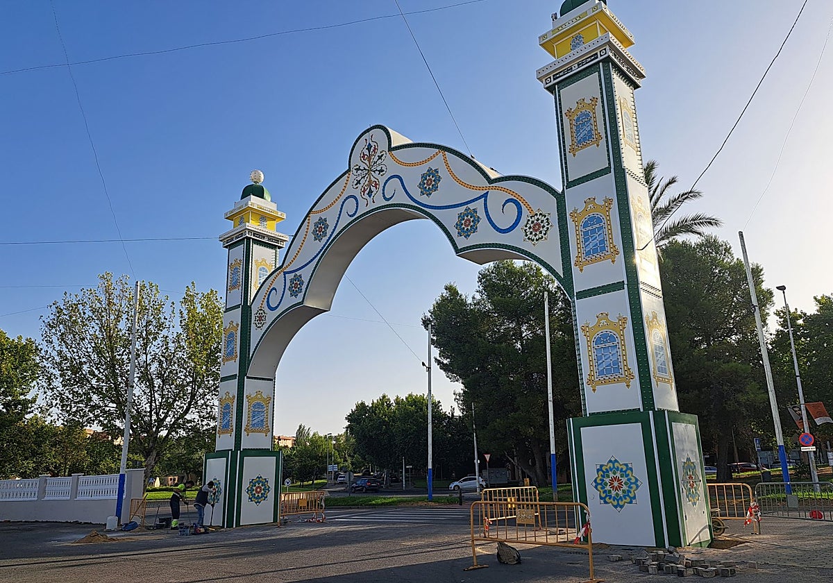 Portada de la Feria ya colocada mientras unos trabajadores limpian una de sus bases, este miércoles.
