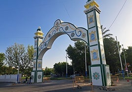 Portada de la Feria ya colocada mientras unos trabajadores limpian una de sus bases, este miércoles.