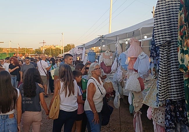 Varias personas ante un puesto de ropa.