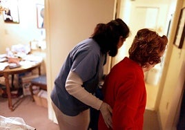 Una cuidadora ayuda a una persona mayor en una imagen de archivo.